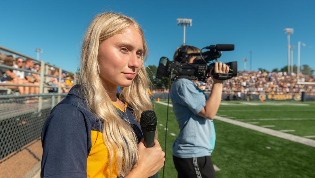A picture of student reporter and camera man at the sport game field