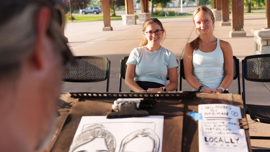 two students having caricature drawn at student event