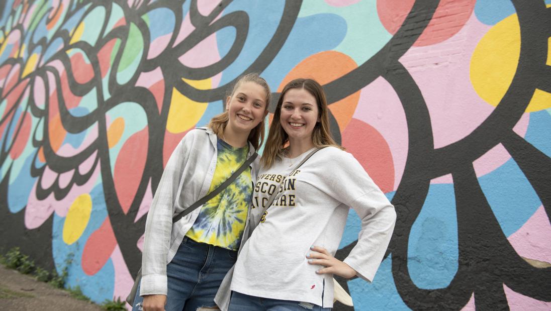two students in front of one of the downtown murals