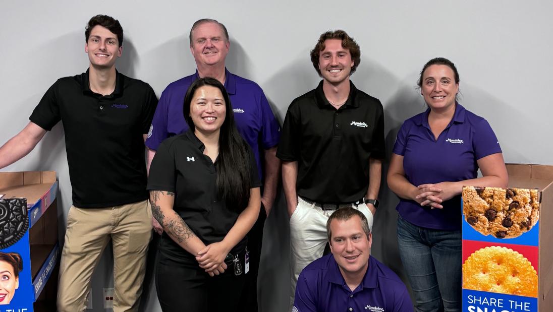 Marketing student, Zach Yuza, standing next to marketing displays with multiple co-workers at his internship at Nabisco