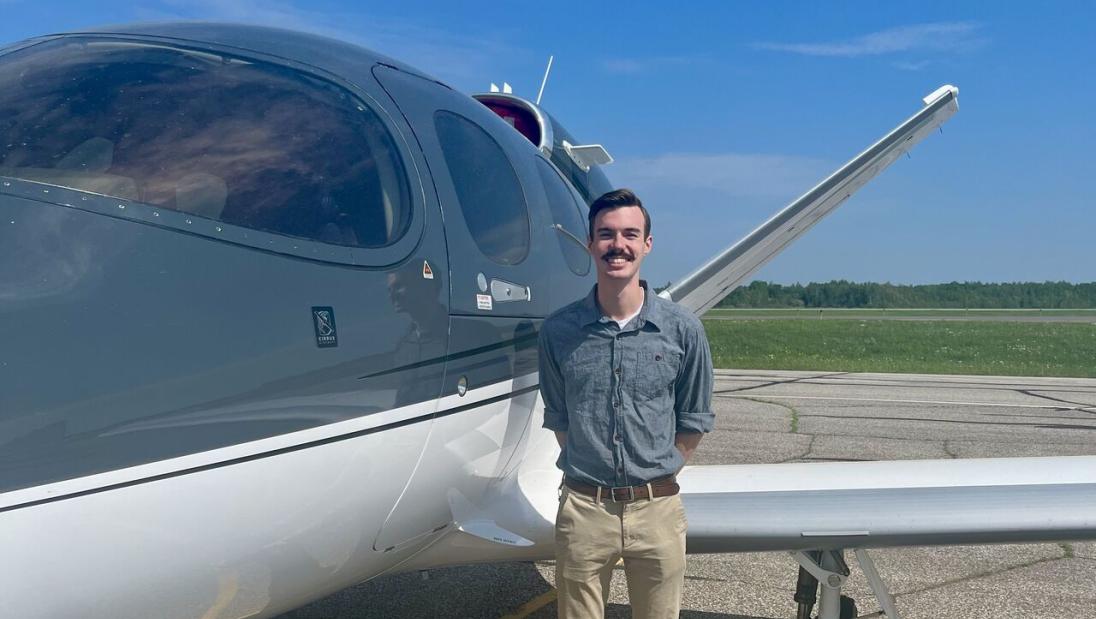 Supply Chain student, Brian Salinas, standing next to airplane during internship at Cirrus Aircrafts.