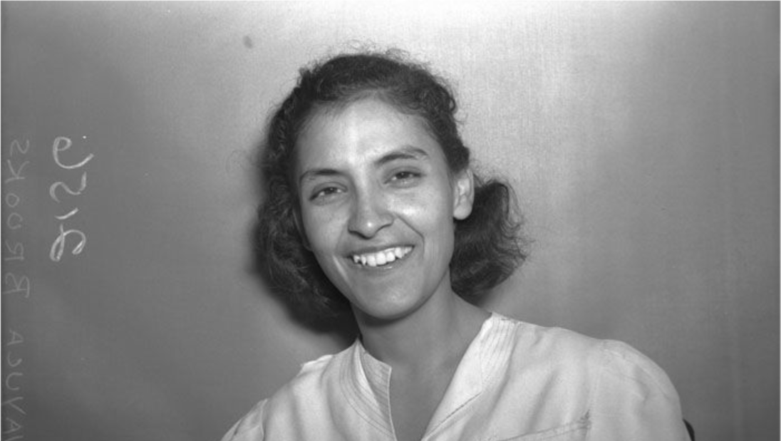 Black and white photo of a young woman smiling at the camera.