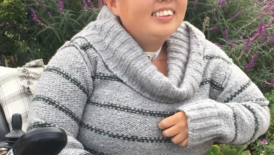 A woman in a wheelchair smiles for the camera.