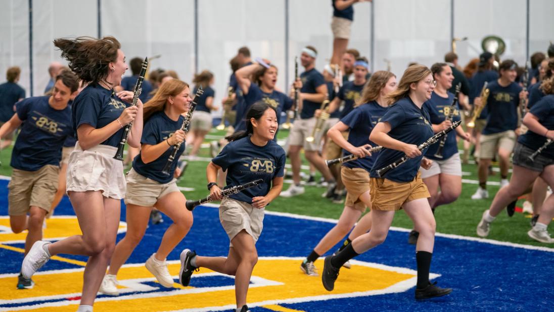 Marching band running onto Sonnentag field house turf