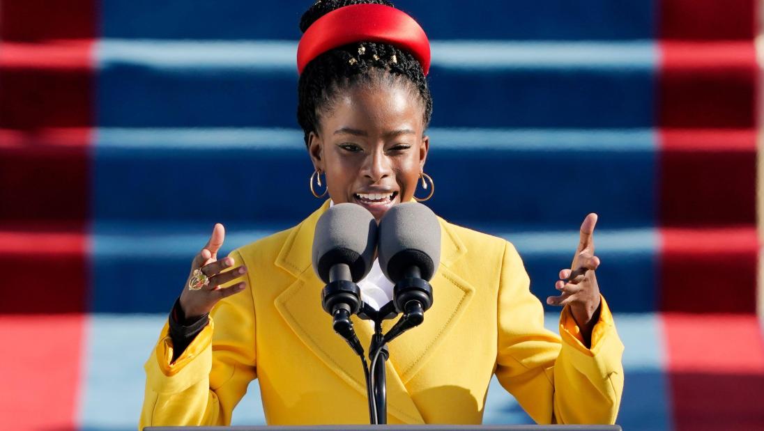 Young Black woman speaking into a microphone at a lecturn.