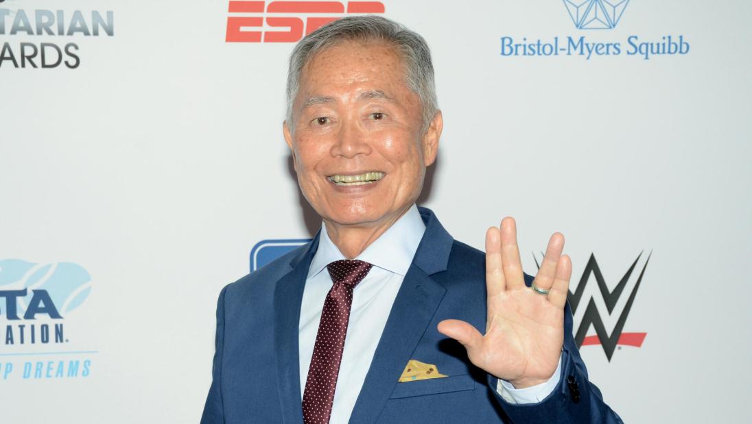 A man smiles at the camera holding up the Star Trek hand gesture.