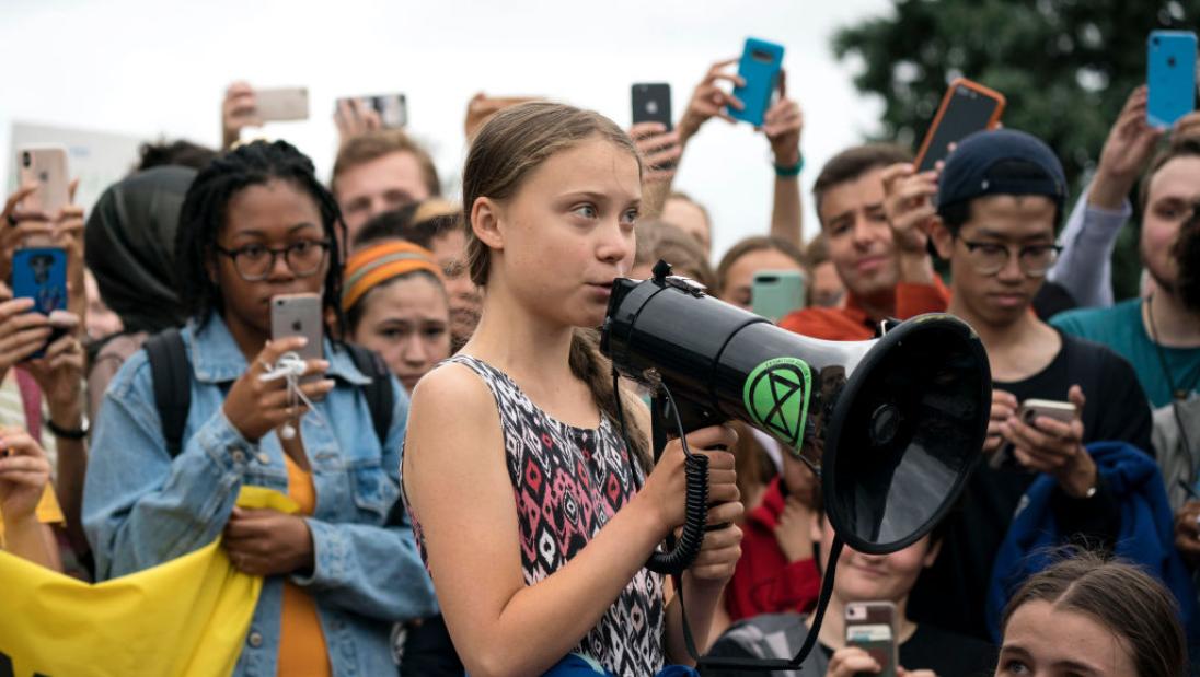 A young girl speaks into a megaphone to a crowd.