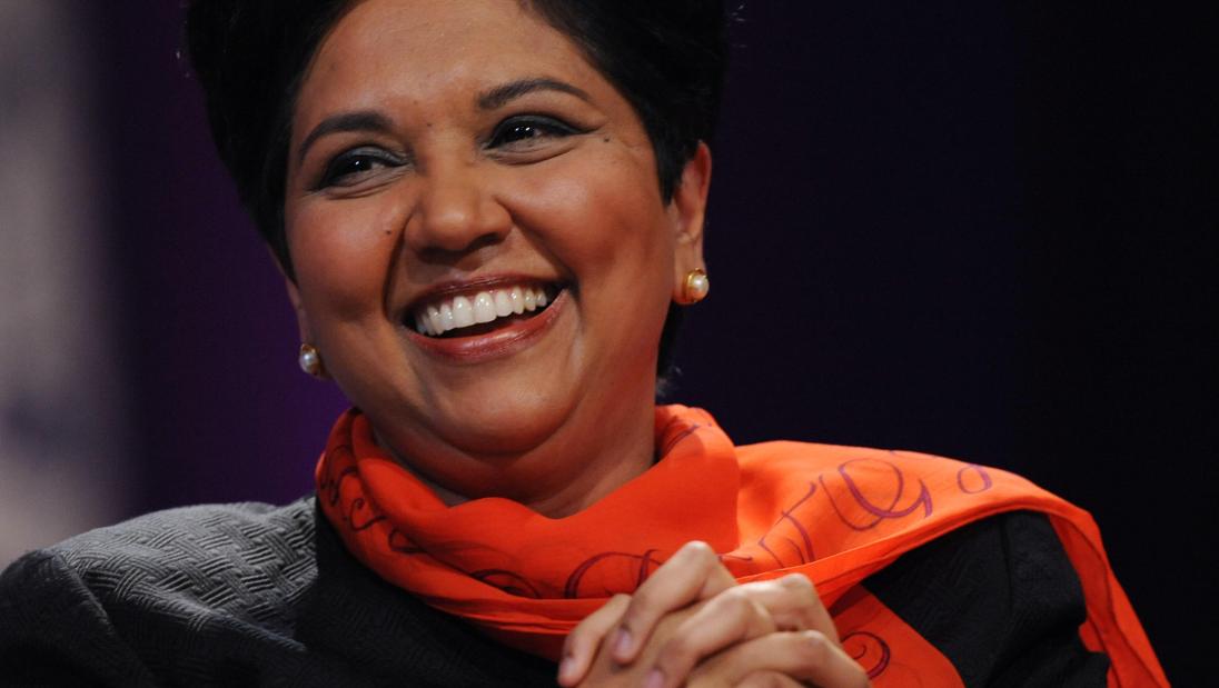 A woman smiles for the camera, with her hands folded in front of her.