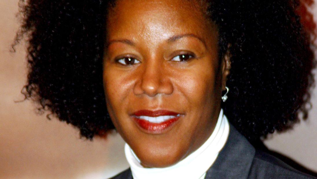 A black woman with an afro smiles for a portrait.