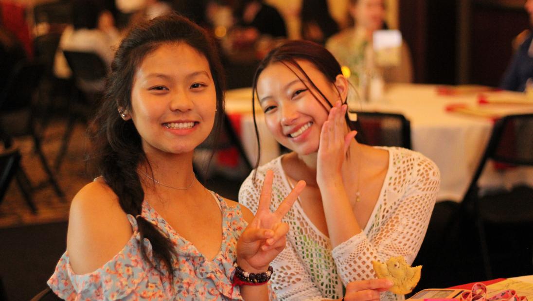 Two Multicultural Student Services students posing for a photo while seated at a table