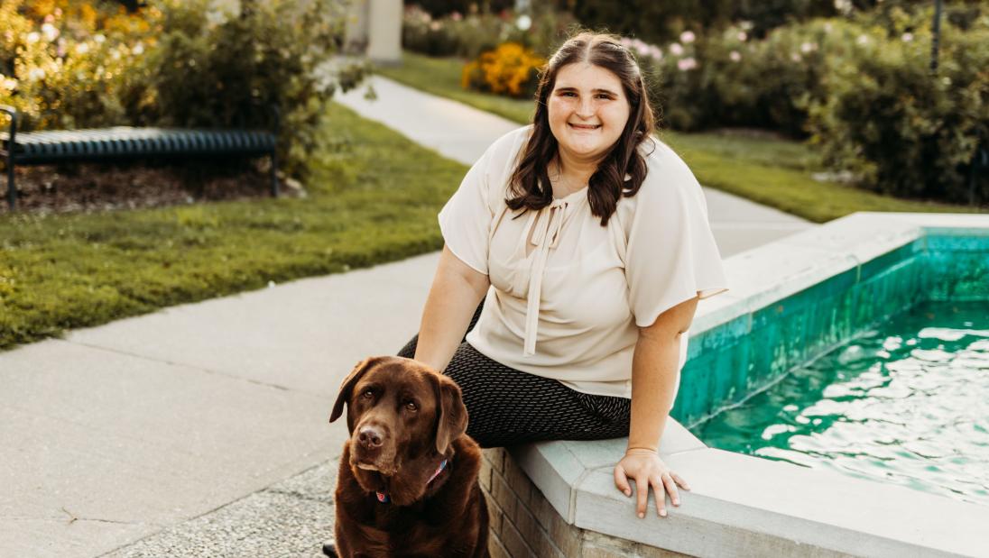 Megan Eilers sits by a concrete pool with her dog, Koda