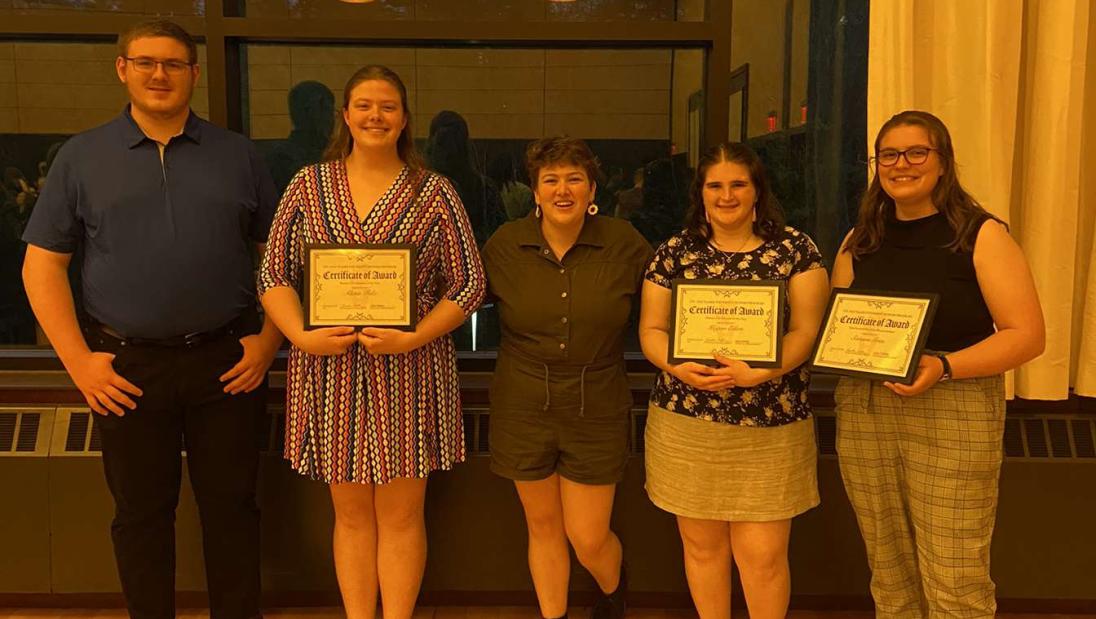 Eilers stands in a group of scholarship recipients with awards on display