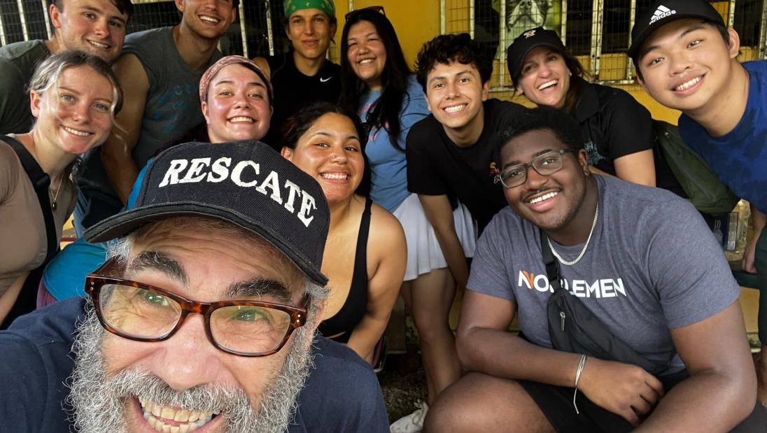 Group selfie with several students and the owner of the dog shelter in front of the shelter