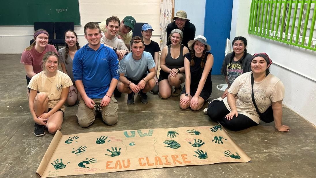 Group of students sitting around a banner with their hand prints.