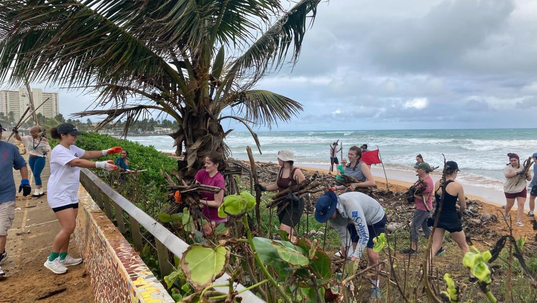 Students picking up branches and debris along the beach in Puerto Rico