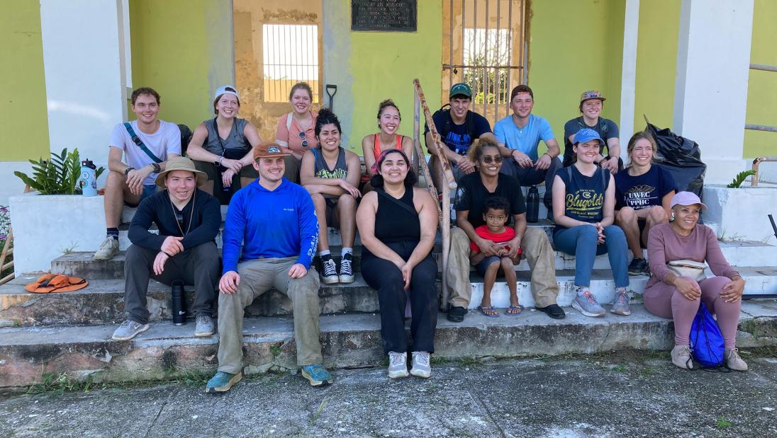 Group photo sitting on steps outside of school the group worked on in Puerto Rico