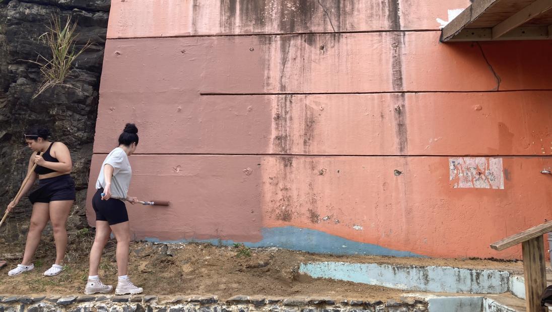 Two students painting a building in Puerto Rico