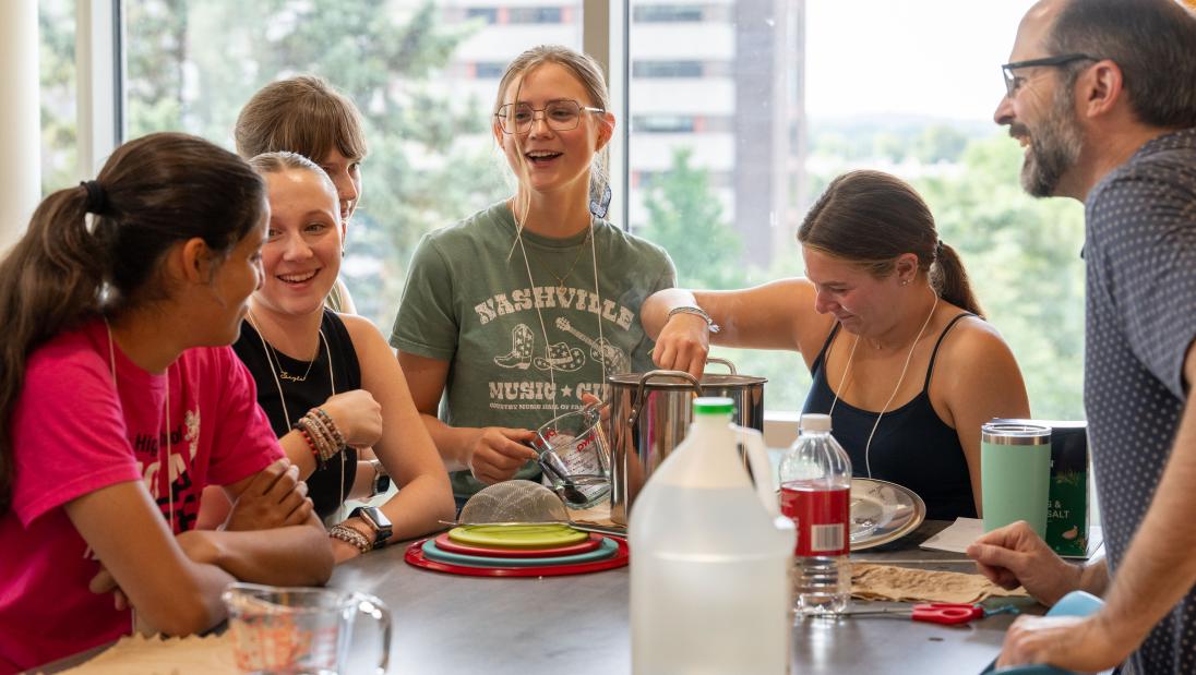 Professor Arndt and students laugh around mixing bowls as they begin to make fermented cheese