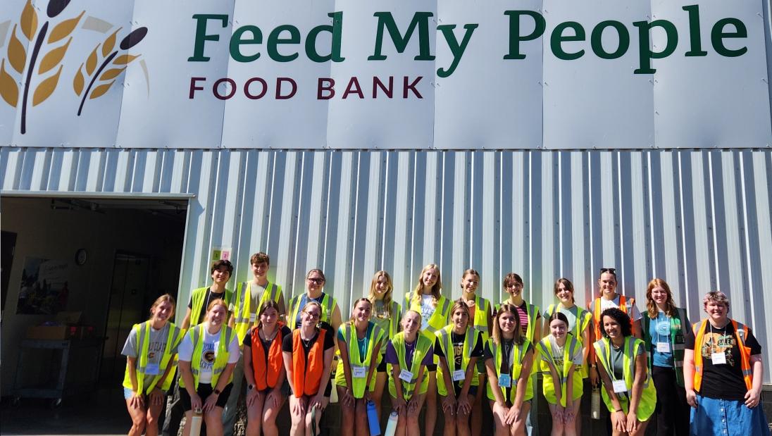 A group of honors student volunteers poses in front of Feed My People Food Bank in Eau Claire