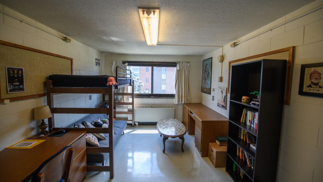 A single room in Bridgman Hall with a lofted twin XL bed, desk, book shelf, and window.