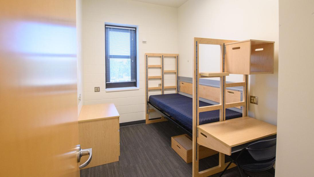 A single room with an XL twin bed, desk and dresser