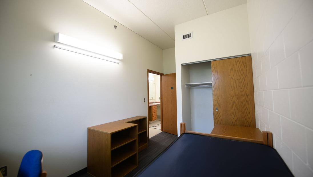 Single bedroom in Chancellors Hall apartment with closet, door opening to bathroom area.