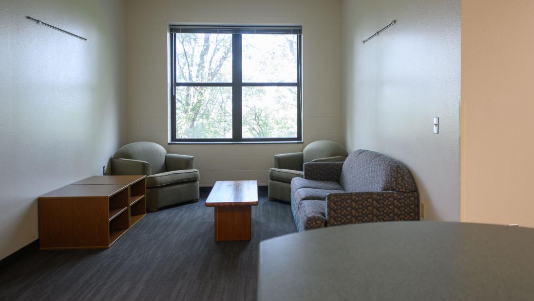 Living room space in a Chancellors Hall apartment with couches and chairs.
