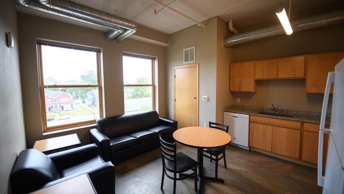 Living area connected to a kitchen, with a couch and an armchair