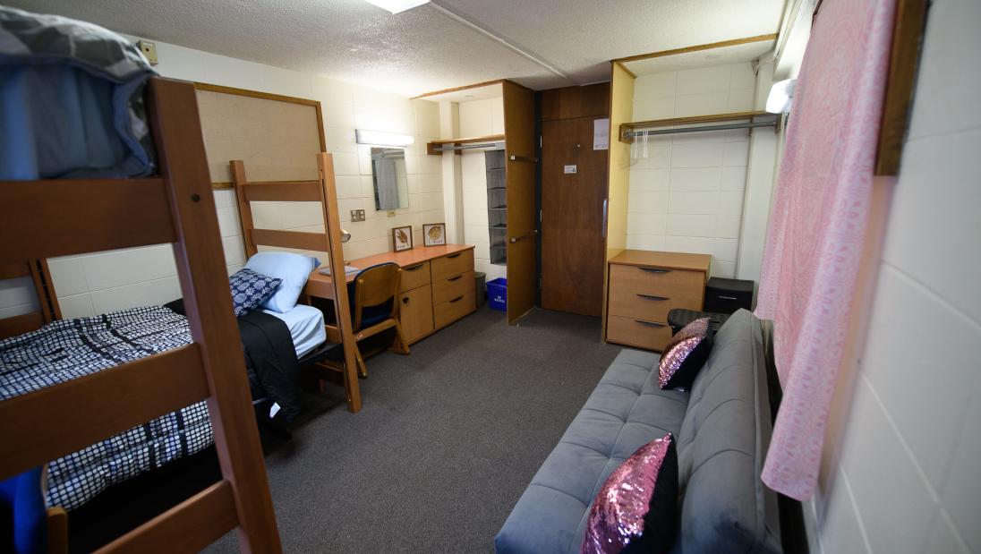 Double room in Governors Hall (viewed from wall opposite door) with two closet spaces, dressers, desks, and beds.
