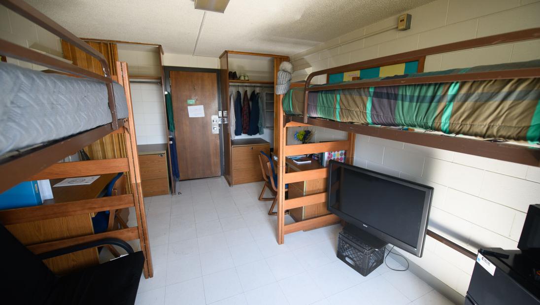 Double room in Horan Hall (viewed from the wall opposite the door) with two beds, chairs, desks, and closet spaces.