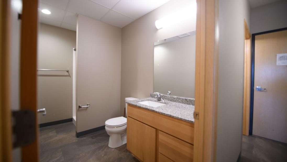 Hallway view of a bathroom with mirror, sink, toilet and a shower