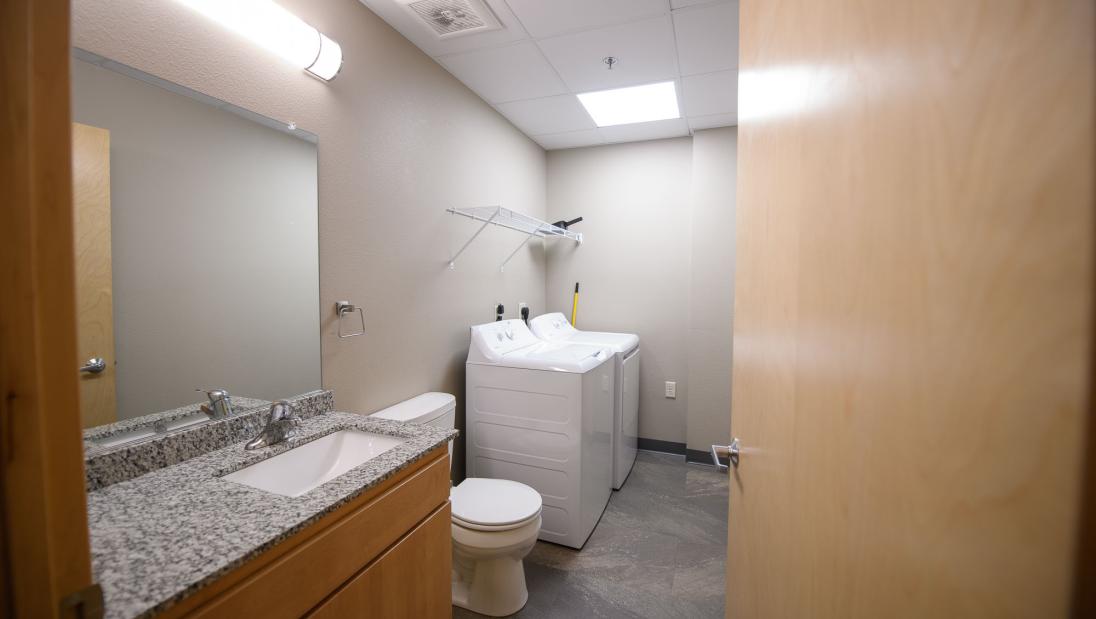 Hallway view of a bathroom with mirror, sink and toilet, plus a washing machine and dryer