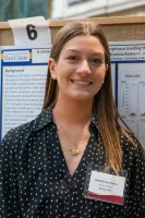 Female student smiling, research poster behind her