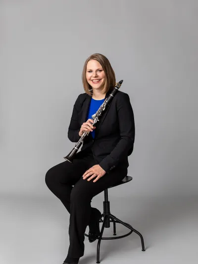 Dr. Alyssa Powell sitting on stool with clarinet.