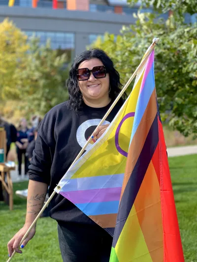 Women with short black hair holding progressive pride flag