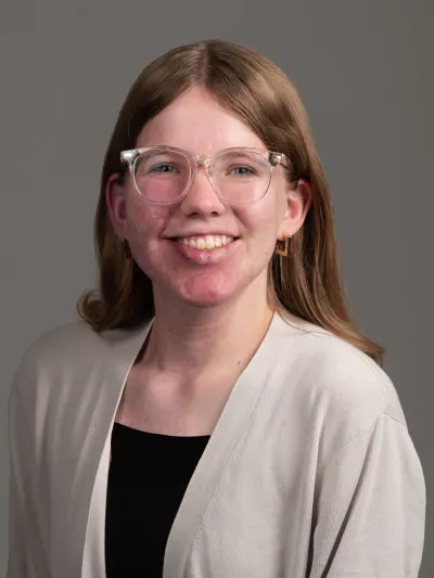 Woman with clear glasses and long dark blonde hair.
