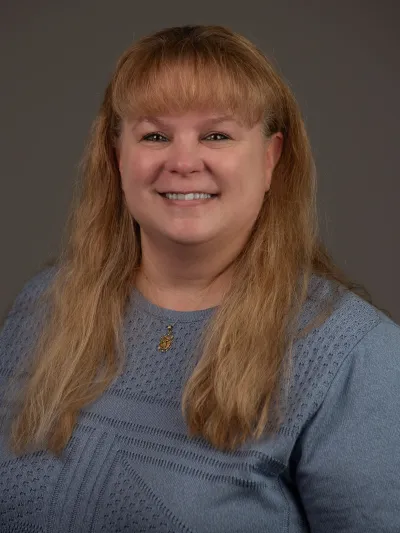 Headshot of woman with long hair wearing a blue blouse.