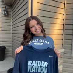 Ally holds up a sweatshirt that reads "Raiders".