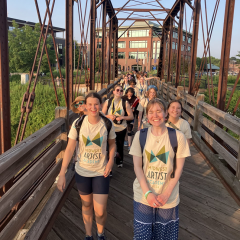 Students wearing "Midwest Artist Academy" shirts smile as they walk across a bridge