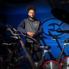 student recreation staff person in cycle studio leaning on a bike