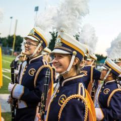 Blugold Marching Band members smile while in uniform at a performance