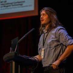 Reed Oberg presenting his research at a podium.