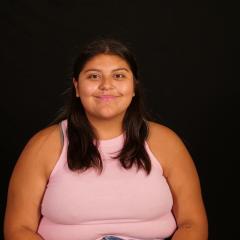 Emma Velazquez poses for camera in front of black backdrop.