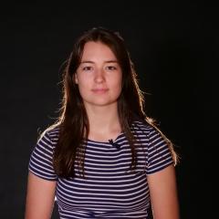 Neala poses for the camera in front of a black backdrop.