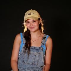 Zoe smiles for camera in front of black backdrop.