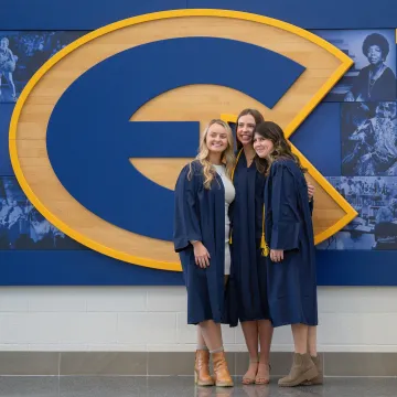 three friend posing for grad picture in front of E logo in Sonnentag 