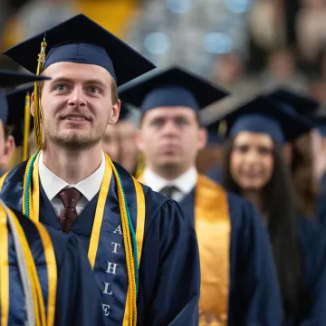 row of graduates in caps and gowns looking forward as entering 