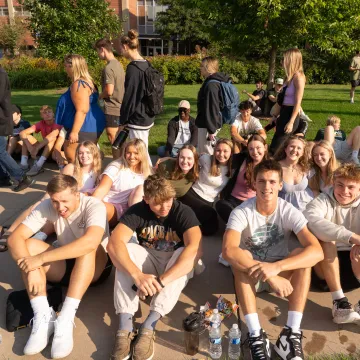 Students in a group sit down and smile during UWEC Welcome Week.