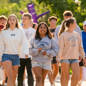 A group of students walk together outside on campus during Welcome Week.