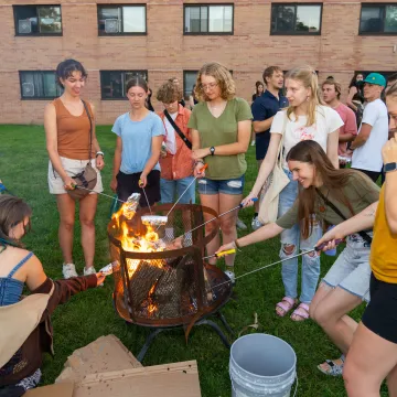 Group of students gathered around a campfire.